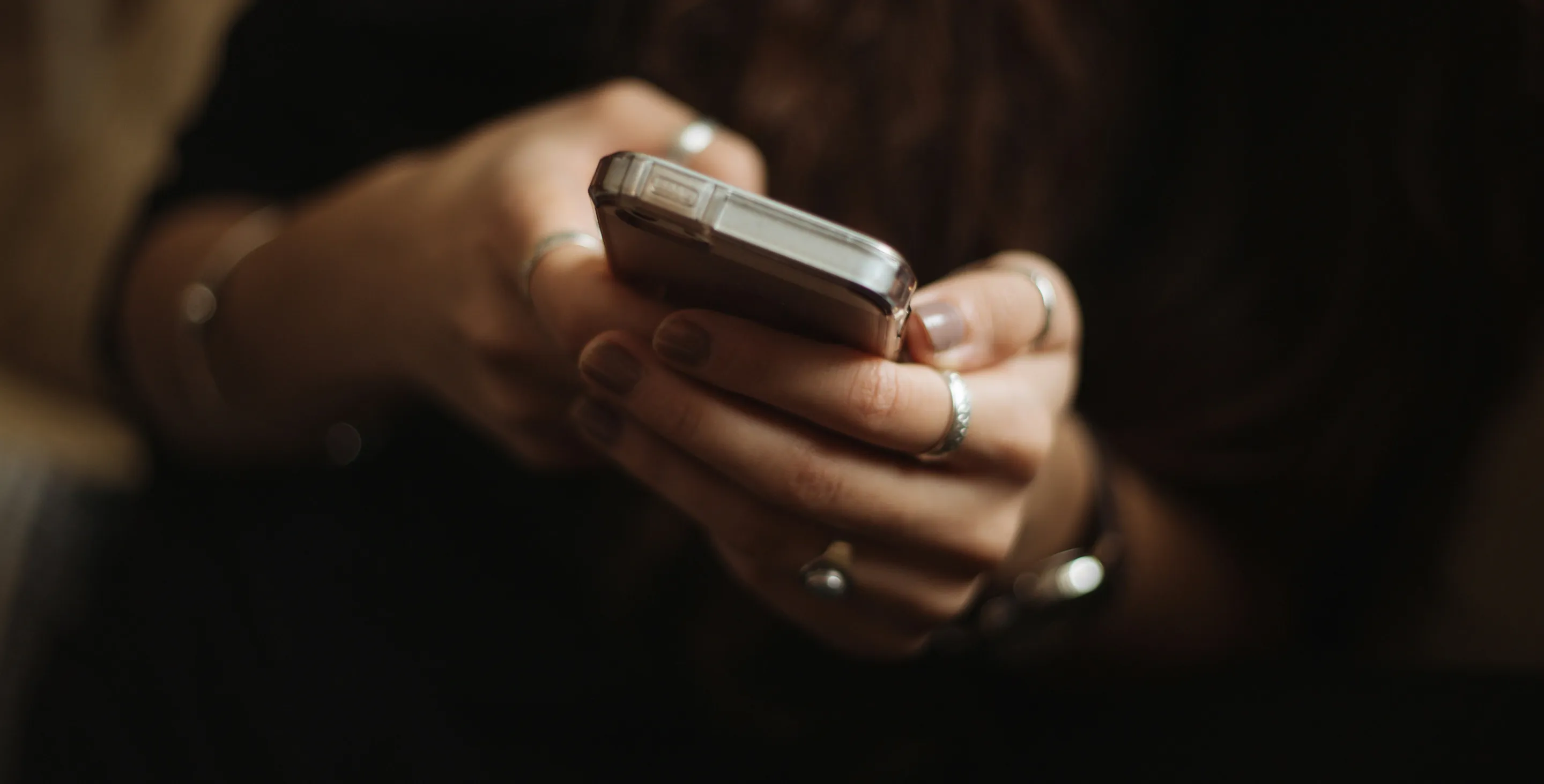 Hands holding a phone in low warm light